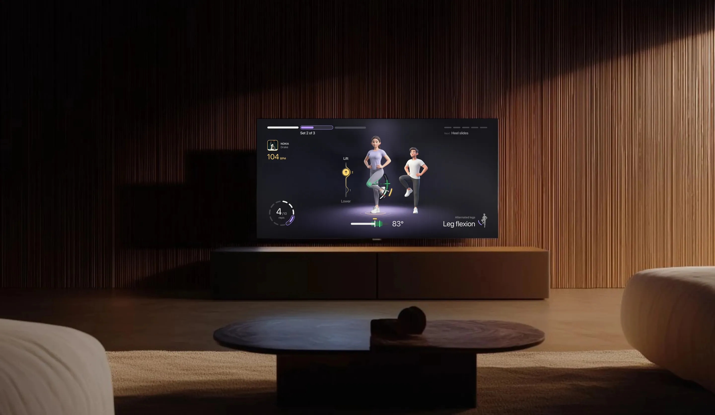 A TV in a dim living room during a leg flexion workout: rep 4 of 10, the athlete’s avatar mirrored next to the coach, the knee at 83° and the track playing at 104 BPM.